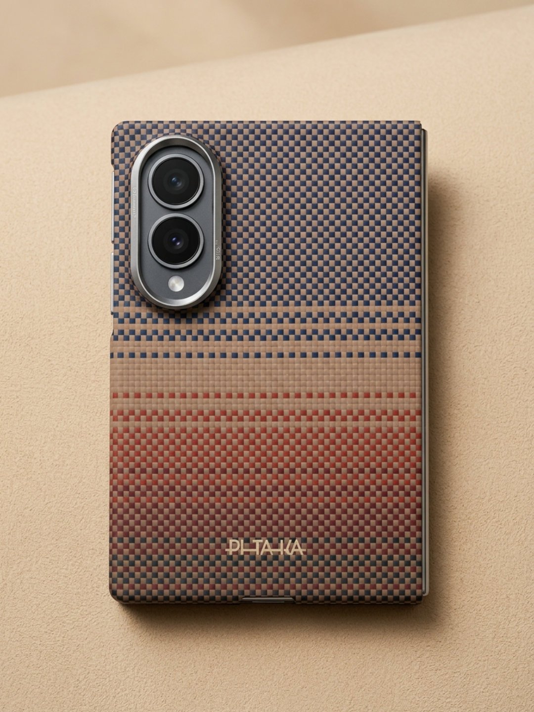 Rear view of a slim phone case showing a fine woven gradient transitioning from navy blue at top to tan and terracotta red at bottom with an oval camera frame.