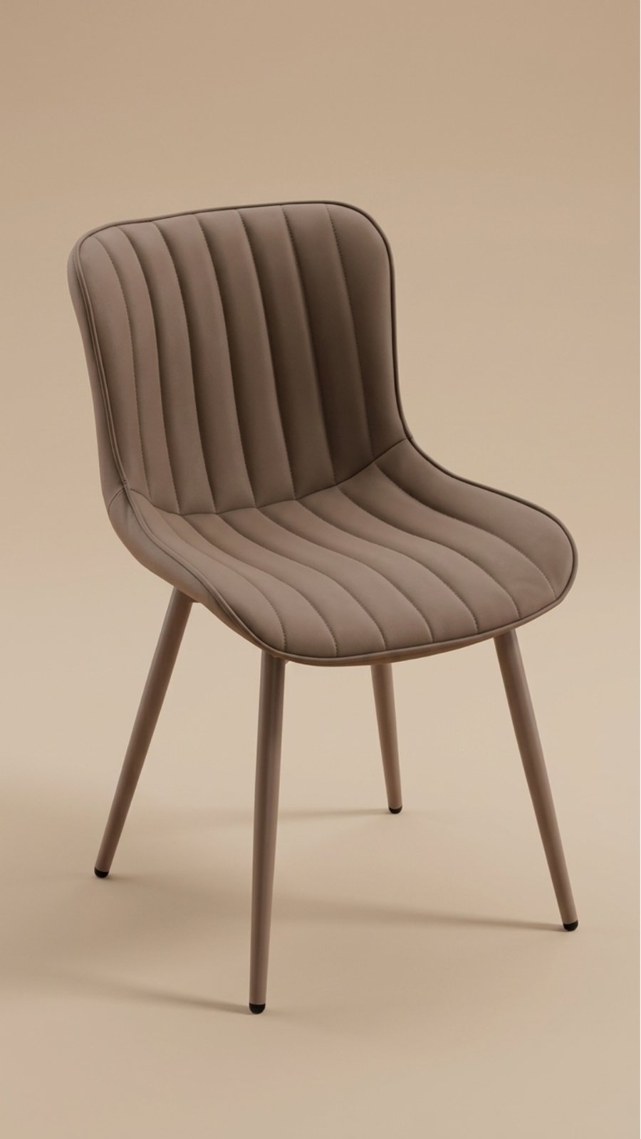 A channel-tufted dining chair in matte taupe upholstery with matching slender taupe metal legs set against a beige studio backdrop.