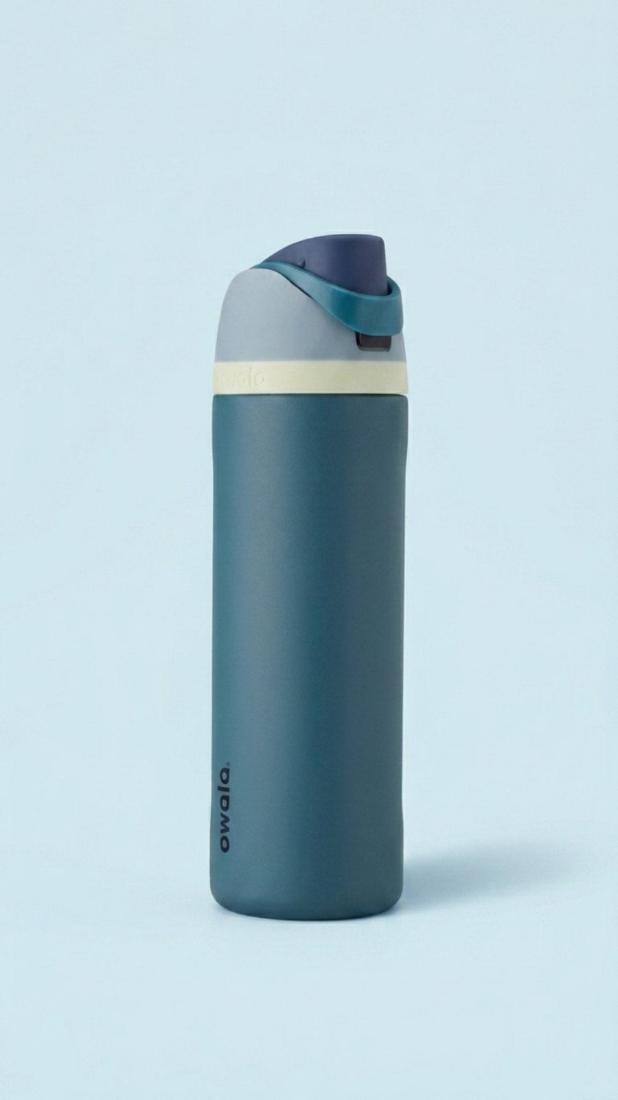A tall, color block insulated water bottle with a dark teal body, light gray top, pale yellow band, and a deep navy blue mouthpiece with a matching teal carrying loop, set against a light blue background.